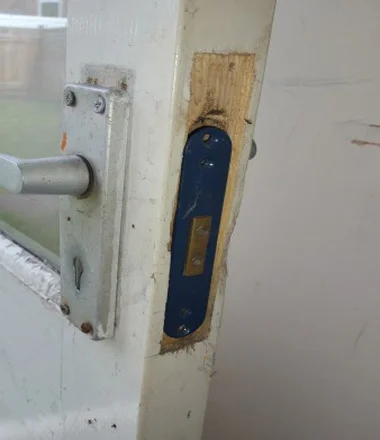Bodged lock fitting - lock case crudely hacked into a UPVC door